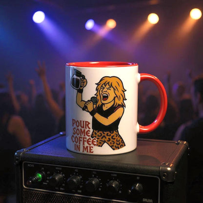 A white coffee mug featuring an illustration of a glam rock musician with teased hair and the phrase "Pour Some Coffee In Me" against a blurred concert background.