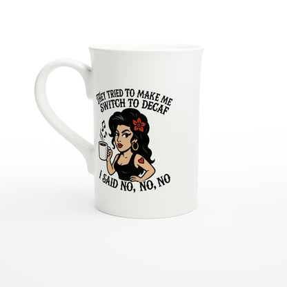 A white coffee mug features an illustration of Amy Winehouse holding a cup and text reading "They tried to make me switch to decaf, I said no, no, no.