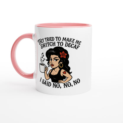 A pink coffee mug displays a cartoon illustration of a woman holding a cup while text reads "They tried to make me switch to decaf" and "I said no, no, no.