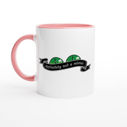 A white mug with a pink handle and interior features a cartoonish D&D mimic illustration and the words "definitely not a mimic" on a banner.