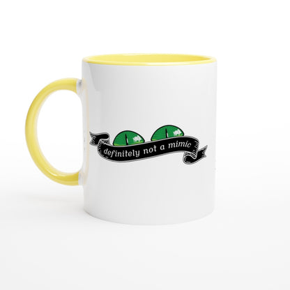 A white D&D mug with a yellow handle and rim features a cartoonish mimic face graphic and the words "definitely not a mimic" on a banner.