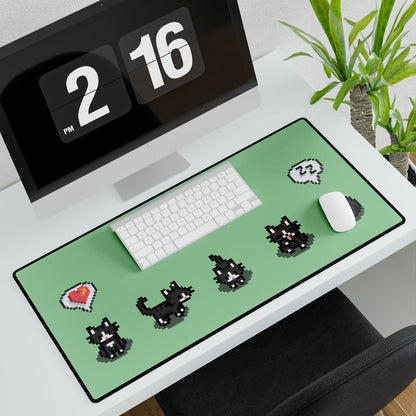 A top-down view shows an extra large desk mat featuring a black and white pixelated cat pattern inspired by Stardew Valley, alongside a keyboard, mouse, and digital clock on a white desk.