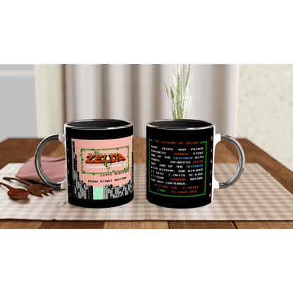 A black mug displays a design referencing The Legend of Zelda NES title screen on one side and vintage game text on the other.