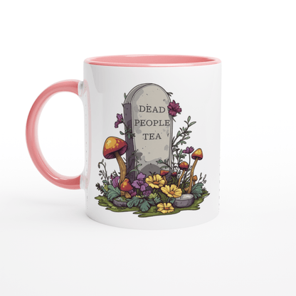 A white ceramic mug with a pink handle and rim features an illustration of a tombstone surrounded by flowers and mushrooms that reads "Dead People Tea.