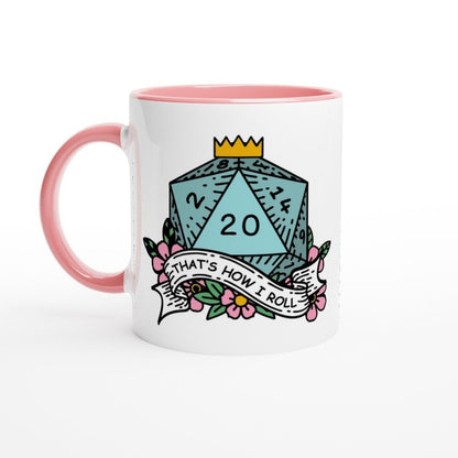 A white mug with a pink handle features an illustration of a D20 die displaying "20" and a banner reading "That's How I Roll.