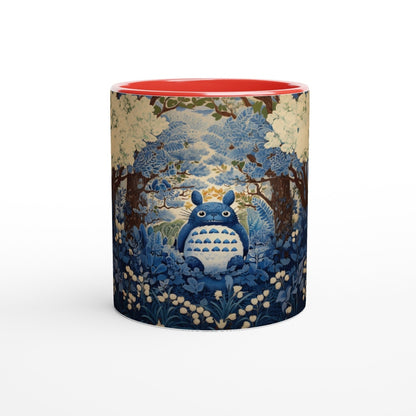 A ceramic mug depicts Totoro from Studio Ghibli sitting within a blue and gold chinoiserie-style cherry blossom forest scene.