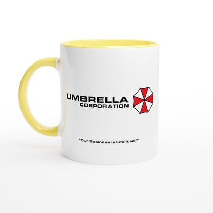 A white mug features a yellow rim and displays the Umbrella Corporation logo and text from Resident Evil referencing "Our Business is Life Itself.