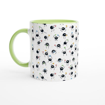 A white ceramic mug with a green handle and rim features a pattern of black Susuwatari, also known as dust sprites from Spirited Away.
