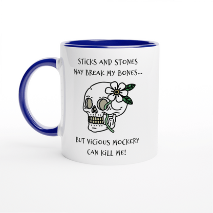 A white mug with a blue rim and handle features text referencing "Sticks and Stones" and "Vicious Mockery," along with an illustration of a skull adorned with flowers.