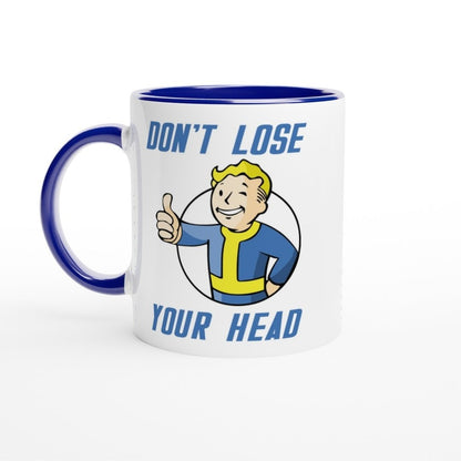 A white mug with a blue rim and handle features Vault-Tec branding and cartoon imagery with the words "Don't Lose Your Head.