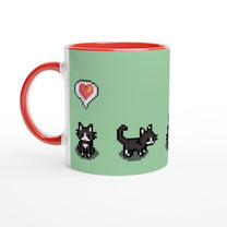 A white mug features pixelated graphics from Stardew Valley depicting tuxedo cats and a heart emote against a light green background with a red interior and handle.