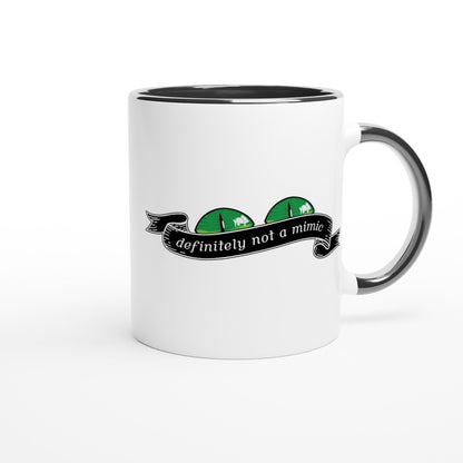 A white mug with a black interior and handle features a decorative banner reading "definitely not a mimic" alongside stylized green monster faces referencing D&D.