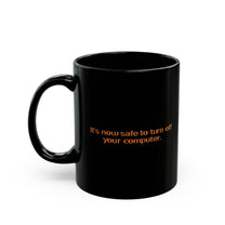 A black mug featuring the Windows 95/98 text It's now safe to turn off your computer in orange lettering.