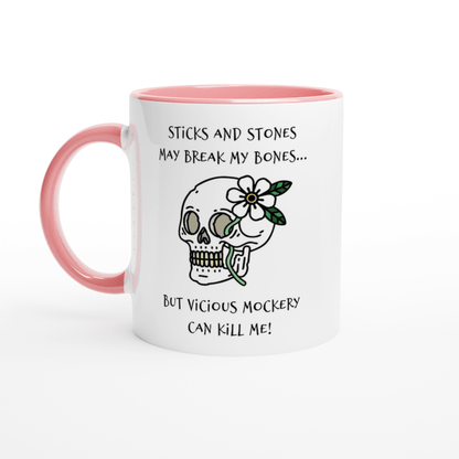 A white mug with a pink handle features text referencing "Sticks and Stones" and "Vicious Mockery," along with an illustration of a skull adorned with a flower and leaves.