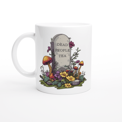 A white ceramic mug displays an illustration of a tombstone surrounded by flowers and mushrooms with "Dead People Tea" inscribed on it.