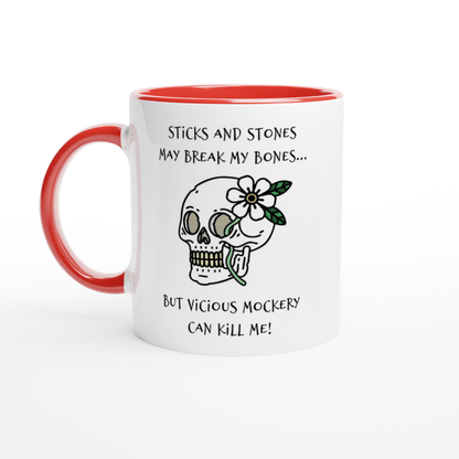 A white mug with a red handle and rim features text referencing "Sticks and Stones" and "Vicious Mockery," along with an illustration of a skull decorated with flowers.