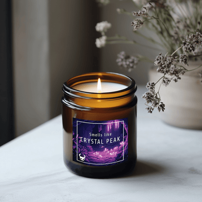 A lit candle in a brown jar displays a label reading "Smells like CRYSTAL PEAK" and featuring Hollow Knight imagery.