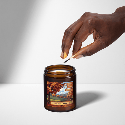 A hand extinguishes a Stardew Valley personalised scented candle featuring an autumnal landscape and custom farm name label.