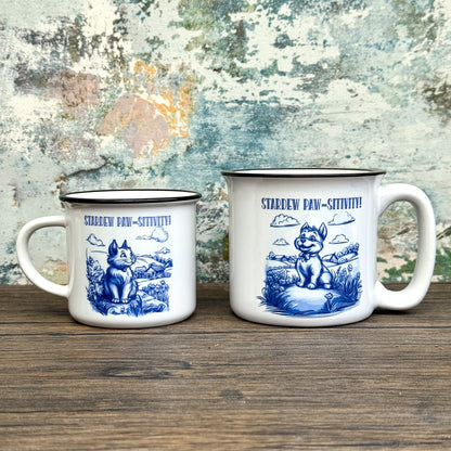 The Quirkify Stardew Valley Chinoiserie Campfire Mug is a blue and white toile ceramic cup featuring house, tree, and mountain artwork with "Stardew Valley" printed on it, displayed on a wooden surface against a multicolored wall.