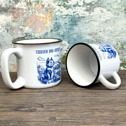 The Quirkify Stardew Valley Chinoiserie Campfire Mug is a blue and white toile ceramic cup featuring house, tree, and mountain artwork with "Stardew Valley" printed on it, displayed on a wooden surface against a multicolored wall.