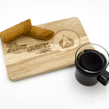 A wooden chopping board labeled "Tea, Earl Grey, Hot" features a Starfleet delta logo and displays a cup of tea alongside a pile of what appear to be wafers.