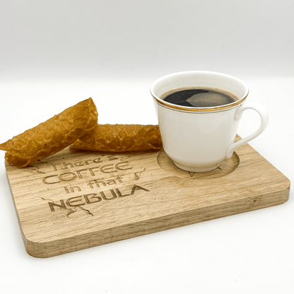 A wooden Voyager chopping board displays the phrase "There's Coffee in that Nebula" and holds a cup of coffee next to a stack of pastries.