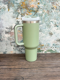 A green 40oz tumbler with a handle sits on a wooden surface against a textured background.