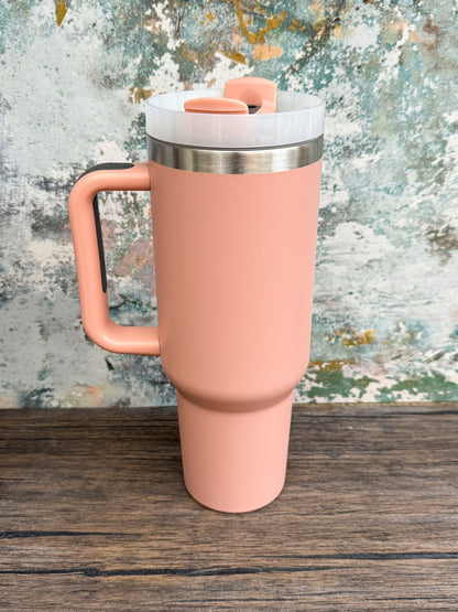 A coral-colored 40oz Witchy Boho engraved tumbler sits on a wooden surface with a textured background.
