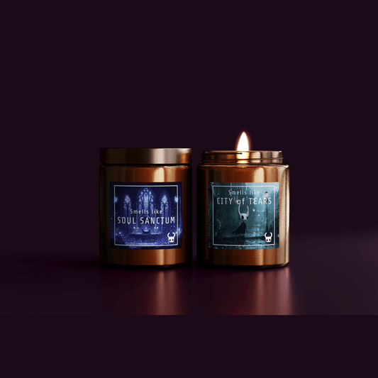 Two Hollow Knight-inspired candles are displayed side by side, one labeled "Soul Sanctum" and the other "City of Tears," both featuring artwork on their labels and one lit with a visible flame.