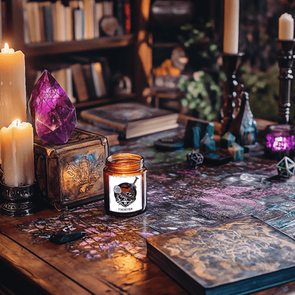 A DnD scented candle labeled "Fighter" sits on a wooden tabletop surrounded by dice, books, crystals, and lit candles, evoking a tabletop RPG atmosphere.