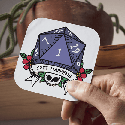 Coaster with a D20 die design, skull, and 'CRIT HAPPENS' text held by a hand.
