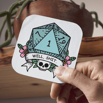 Coaster with a DnDn D20 die design and text held by a hand, with a plant in the background