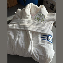 A white folded bathrobe featuring a blue Fallout Vault-Tec 76 logo on the chest.