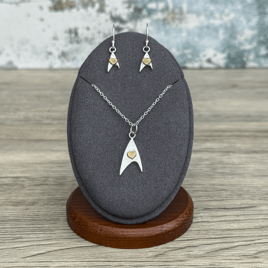 A sterling silver Starfleet emblem earring and pendant set inspired by Star Trek is displayed on a jewelry stand.
