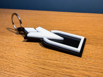 A 3D acrylic keyring featuring a white Skyrim inspired quest marker icon on a black base.