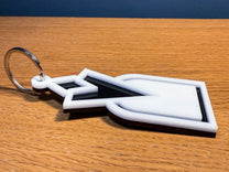 A 3D acrylic keyring featuring a white Quest Marker icon inspired by Skyrim, resting on a wooden surface.