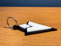 A 3D acrylic keyring featuring a white Skyrim inspired quest marker icon on a black base.