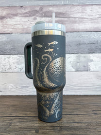 A gray 40oz tumbler features an engraved design of a Kraken octopus and tentacles surrounding a central sphere, inspired by D&D and Cthulu themes.