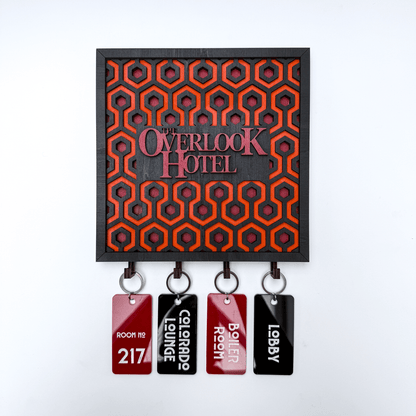 A laser-cut wooden key holder featuring a carpet pattern reminiscent of The Shining and displaying "The Overlook Hotel" lettering, along with five decorative room keys.