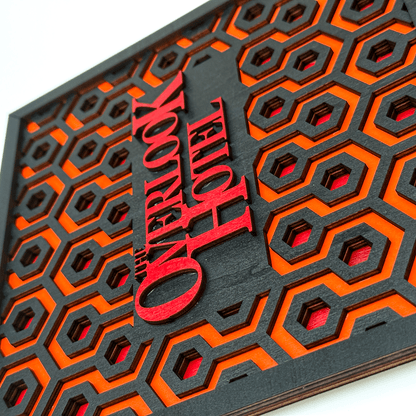 A laser-cut wooden key holder features a repeating carpet pattern inspired by The Shining and displays "Overlook Hotel" in raised lettering.