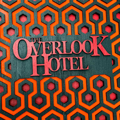 A laser-cut wooden key holder displays "The Overlook Hotel" in red lettering against a backdrop of the iconic carpet pattern from The Shining.