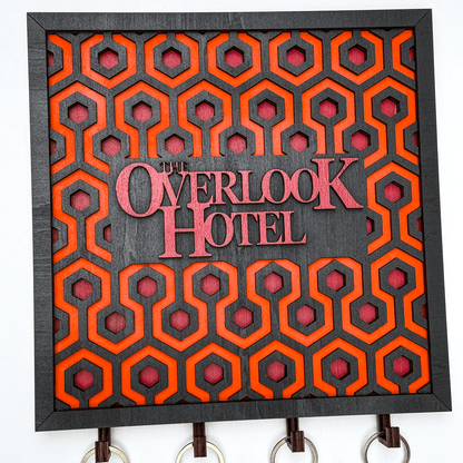 This wooden key holder features a laser-cut carpet pattern inspired by The Shining and displays "The Overlook Hotel" in raised lettering.