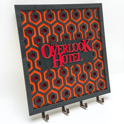 This laser-cut wooden key holder features a carpet pattern design inspired by The Shining and displays "The Overlook Hotel" in bold lettering.
