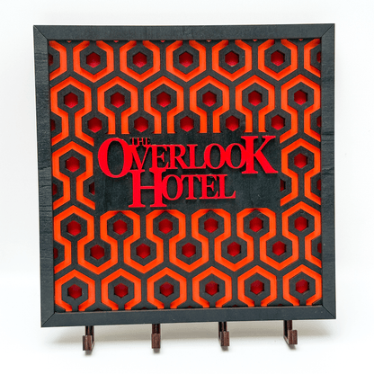 A laser-cut wooden key holder features a repeating carpet pattern reminiscent of The Shining and displays "The Overlook Hotel" in red lettering.