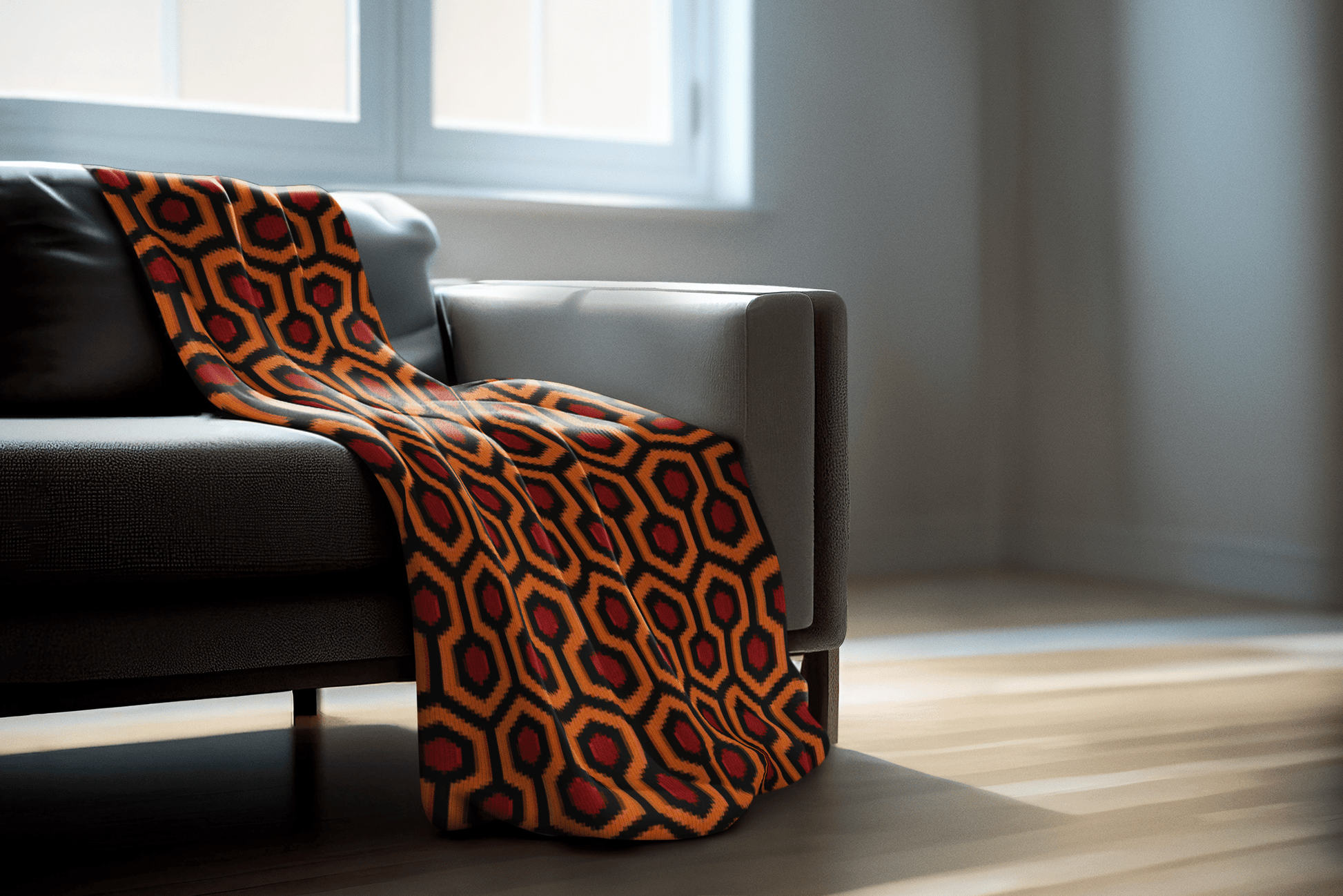 Gray sofa with an Overlook Carpet patterned knit orange and red blanket in a room with large windows.