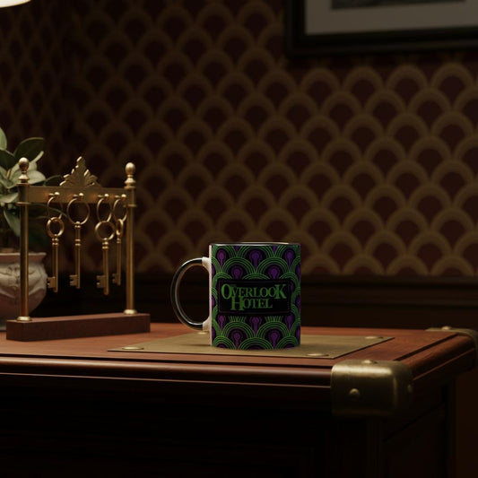 Mug with 'Overlook Hotel' logo and wallpaper pattern from Room 237, on a wooden surface with decorative keys and plant.