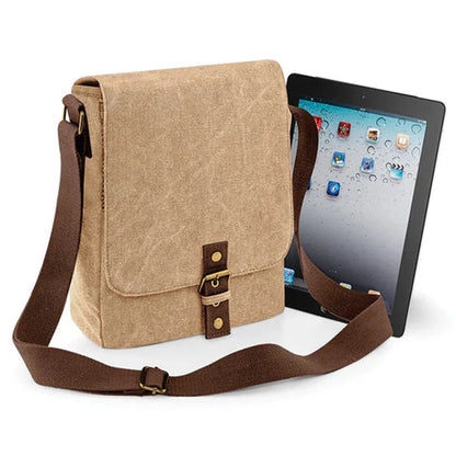 A brown canvas Zelda Sheikah Tablet Bag is shown open with a tablet inside, featuring a flap closure and adjustable shoulder strap.
