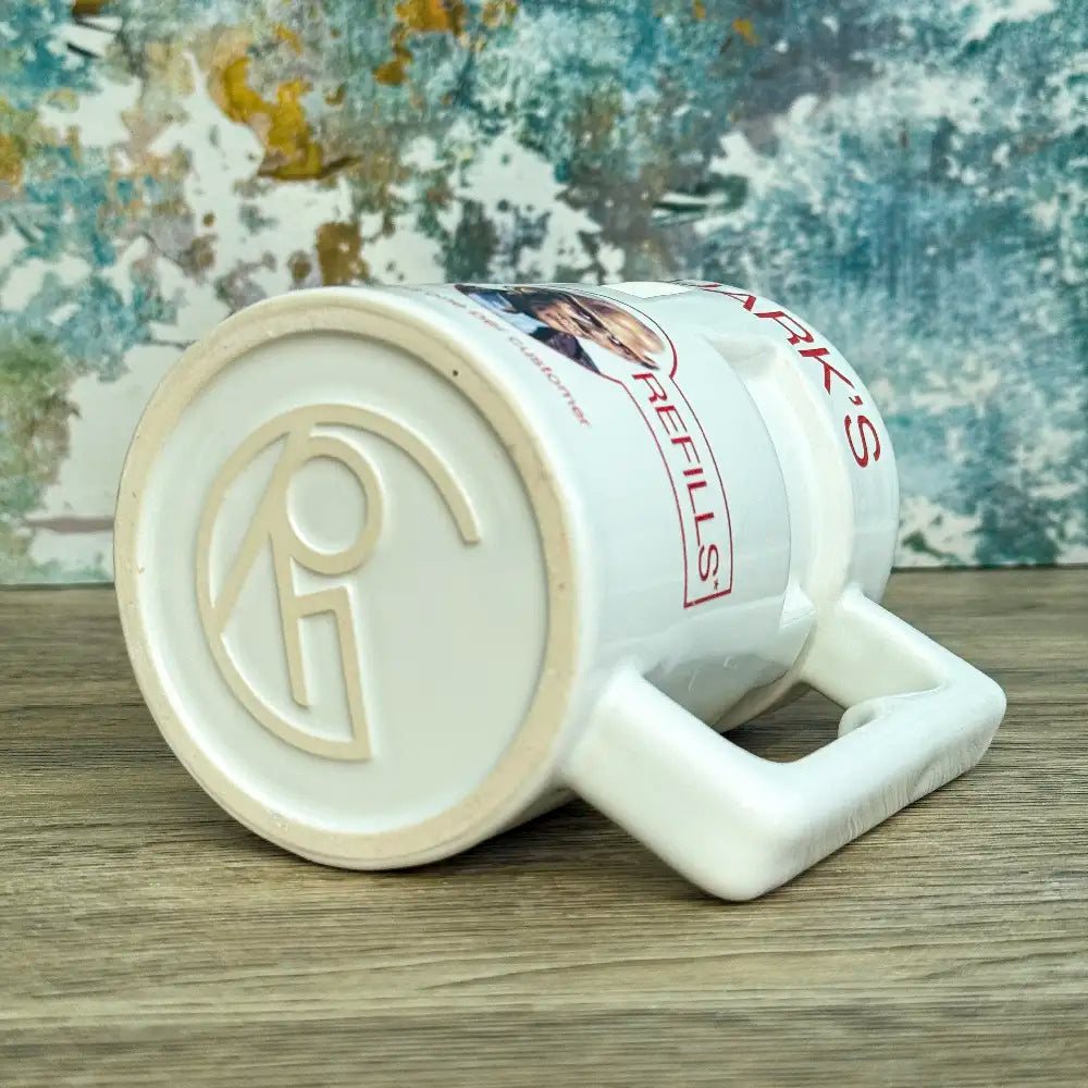 Quarks Bar Mug replica from Star Trek Deep Space Nine labelled "Quark's" with a portrait of Quark and text promoting free refills, against a colourful background