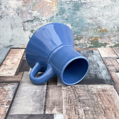 A blue Replica mug, styled like a Klingon Raktajino vessel from Star Trek: Deep Space Nine, rests on a patterned surface.