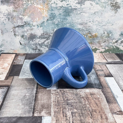 A blue Replimat mug, resembling a Little Blue Raktajino vessel from Star Trek: Deep Space Nine, rests on a textured surface.